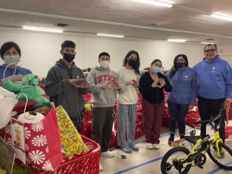 Members of the student council stand with Salvation Army workers in the warehouse where gifts for disadvantaged children are stored before being distributed for Christmas. The Aztec Angel program at El Dorado collected over 200 gifts for children this year. 