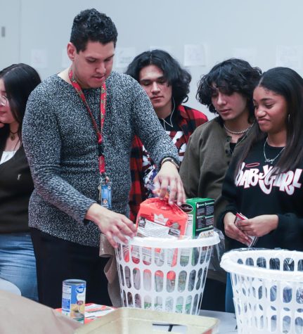 Filling the remaining baskets for a Nov 18 distribution date, Adviser Jacob Ramirez, seniors Marcos Riperto, Alan Martinez and junior Kayla Medford watch as another basket fills with the basic Thanksgiving necessities on Nov 16.