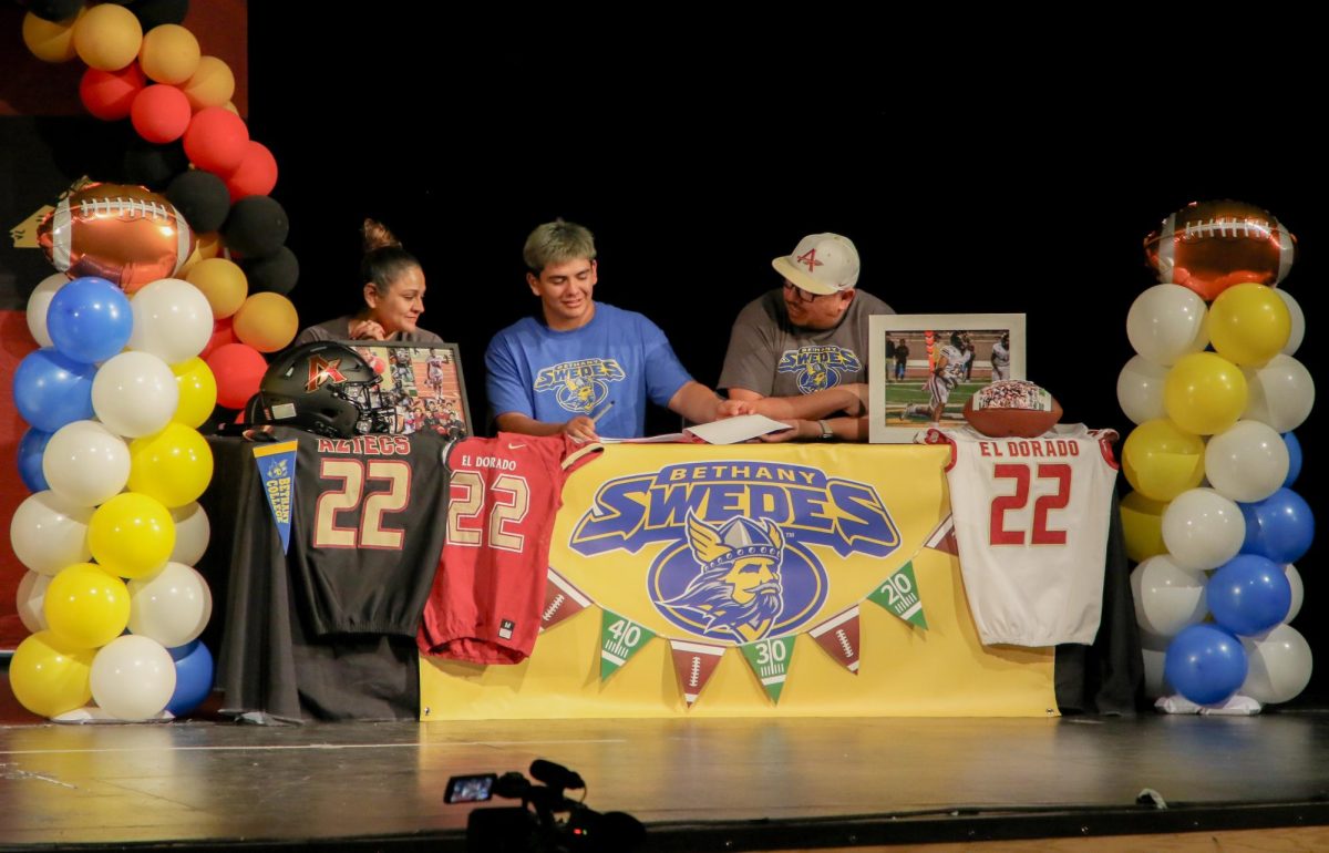 The Pick Is In. Flipping the page, senior David Martinez signs to Bethany College on April 11 alongside his parents in the theater. Martinez worked towards this moment since he was a child. “My mom is a very supportive person, she’s always pushing me to be my best and my dad has always been there for me,” Martinez said.