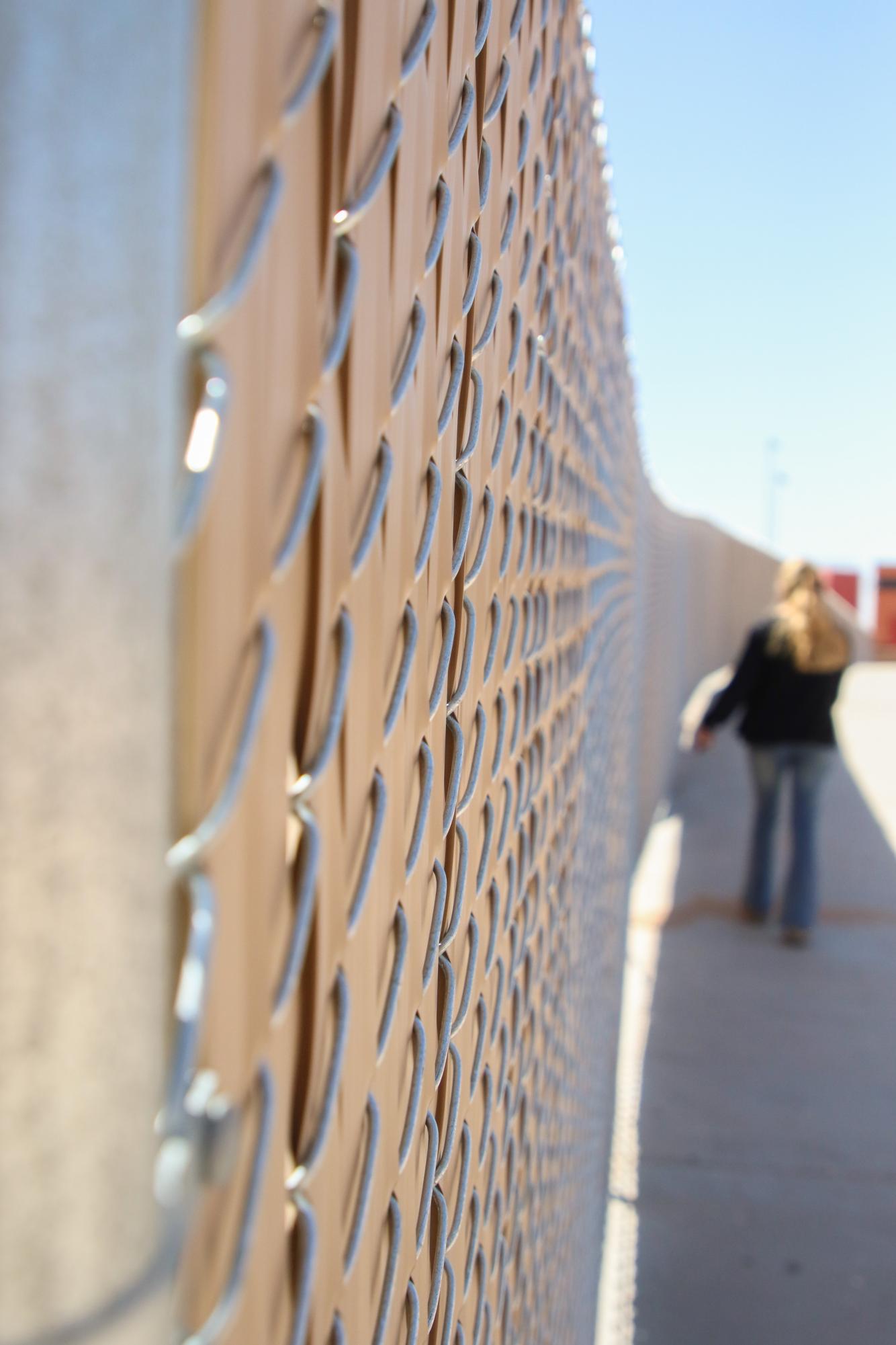 Extra Steps. Taking the long way to get to the student parking lot, senior Mia Jade Colmenero walks along the newly-installed fence alongside the football field on April 16. Instead of walking down the concrete, Colmenero had to walk to the softball field to exit the wall of fences. “I honestly think the gates will cause way more of a safety hazard to us, in case of an emergency we will all be trampled to get out,” Colmenero said. 
